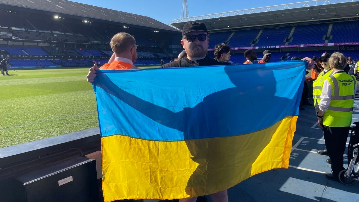 Скандал на матче АПЛ - почему у журналиста Эндрю Тодоса забрали флаг Украины Скандал на матче АПЛ - почему у журналиста Эндрю Тодоса забрали флаг Украины